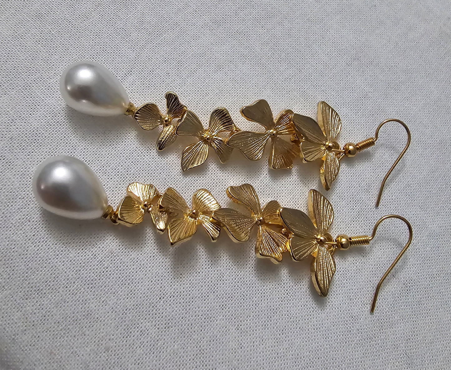 Modern costume earrings, cascade of flowers in gold with a drop pearl at the bottom, bold and stunning.
